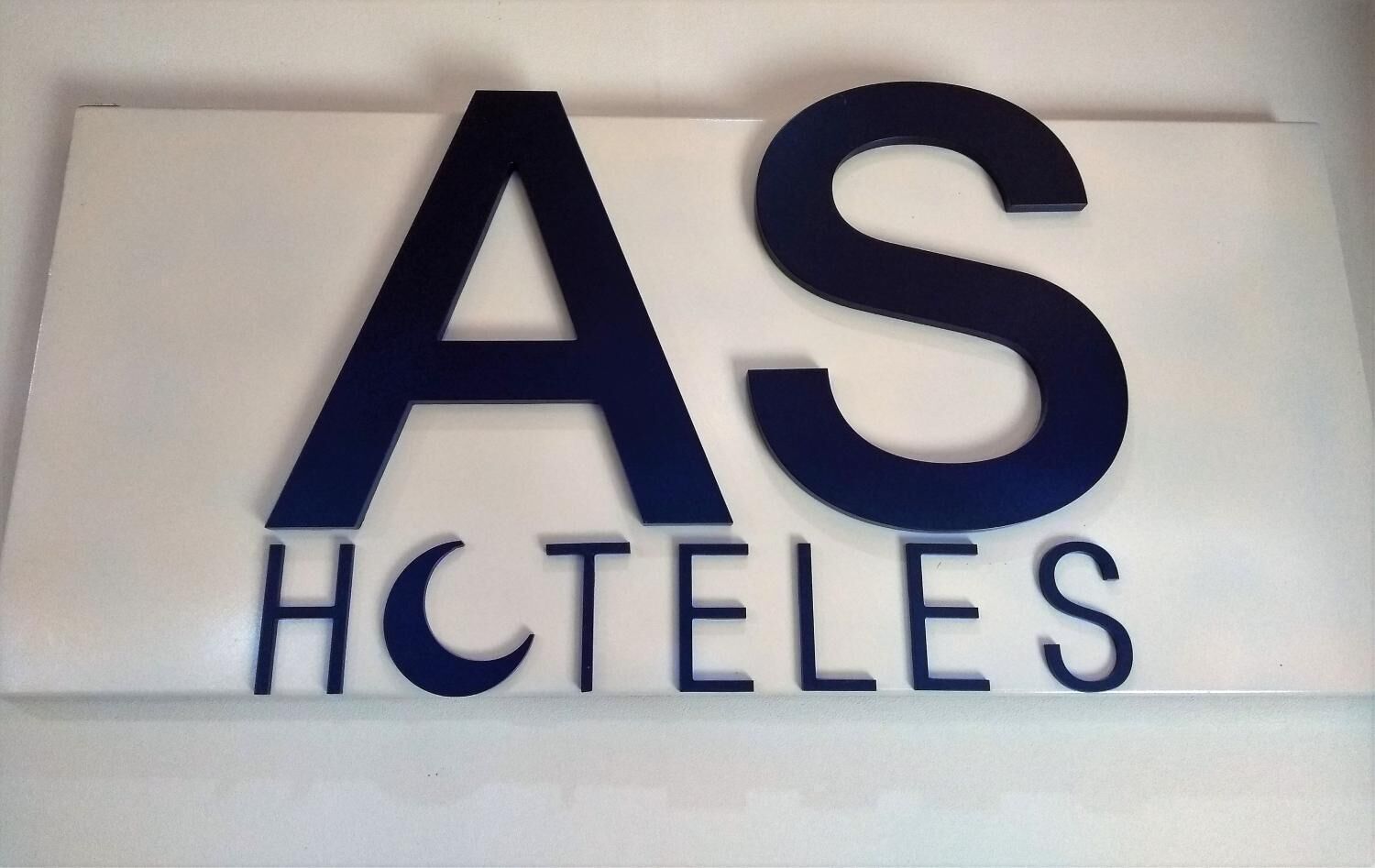 Un senyal amb les lletres "AS" i "HCTELES" en lletra gran i amb negreta, probablement representant una marca d'hotel o allotjament.