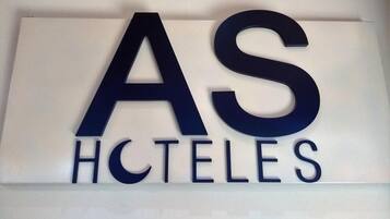 Et skilt med bogstaverne "AS" og "HCTELES" i stor, fed skrift, sandsynligvis et hotels eller boligbrands navn.