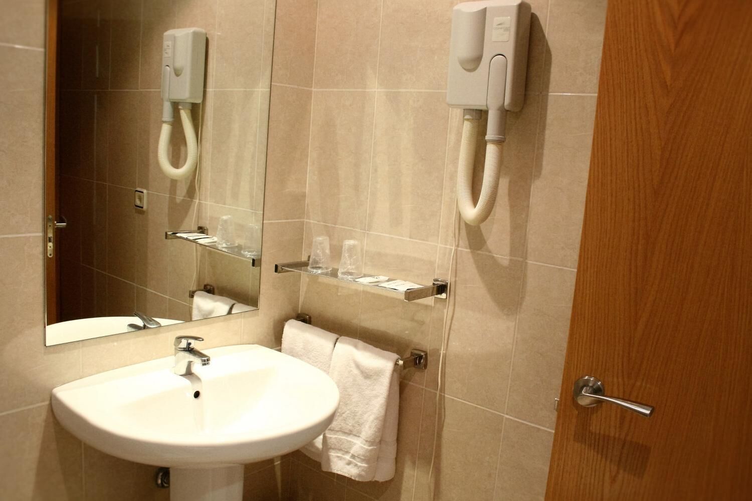 Une salle de bain équipée d’un lavabo, d’un miroir, d’un porte-serviettes et d’une douche avec un pommeau de douche amovible.