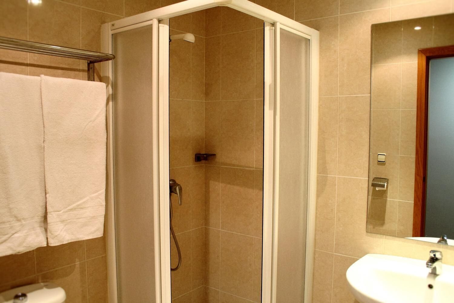 Un baño con ducha a ras de suelo, un lavabo y un espejo.