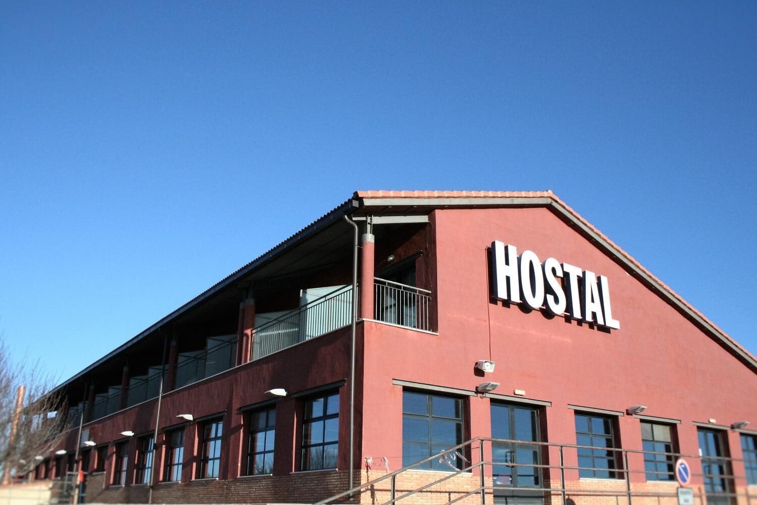 A red building with a sign that reads "HOSTAL" on the side.
