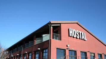 A red building with a sign that reads "HOSTAL" on the side.