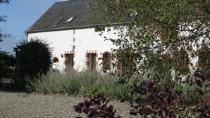 Un bâtiment blanc avec un toit en pente, de nombreuses fenêtres et une allée gravillonnée.