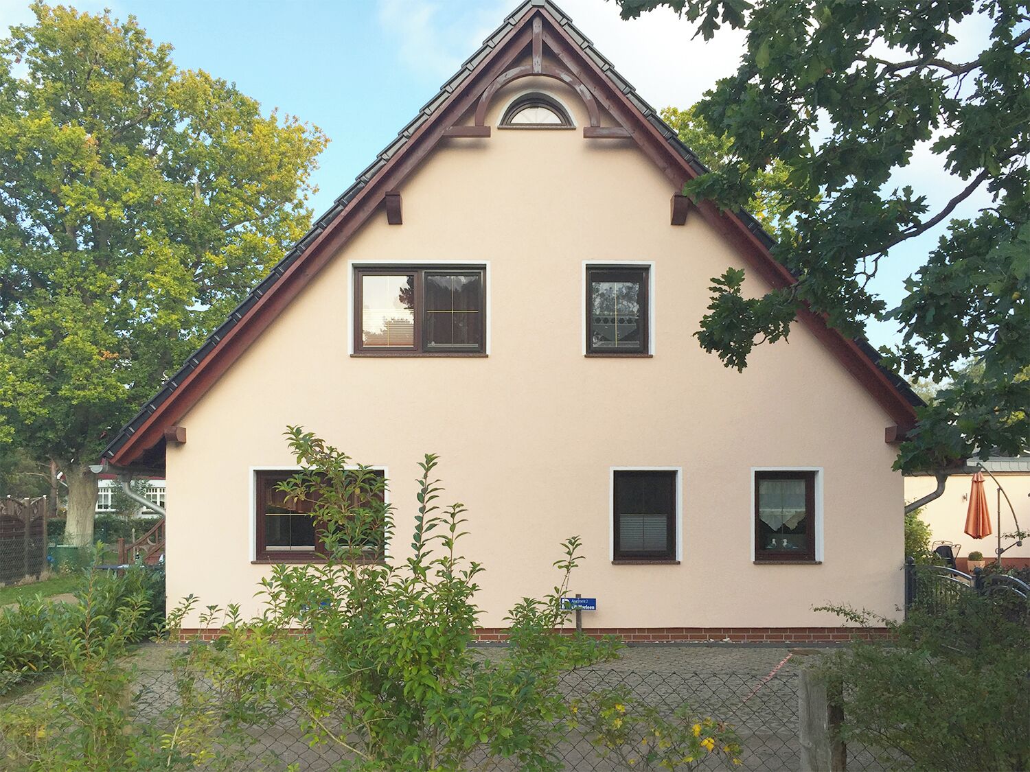 Une maison à deux étages, dotée d’un toit à pignon et d’un petit porche.