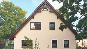 Een huis met twee verdiepingen, een puntige dakschild en een klein portaaltje.