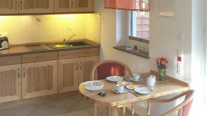 Een compacte keuken met een spoelbak, een broodrooster en een eettafel met stoelen.
