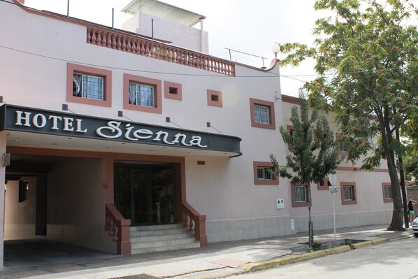 A hotel named 'Hotel Siena' with a modern facade, a staircase leading to the entrance, and a tree in front. - Hotel Sienna (Mendoza)