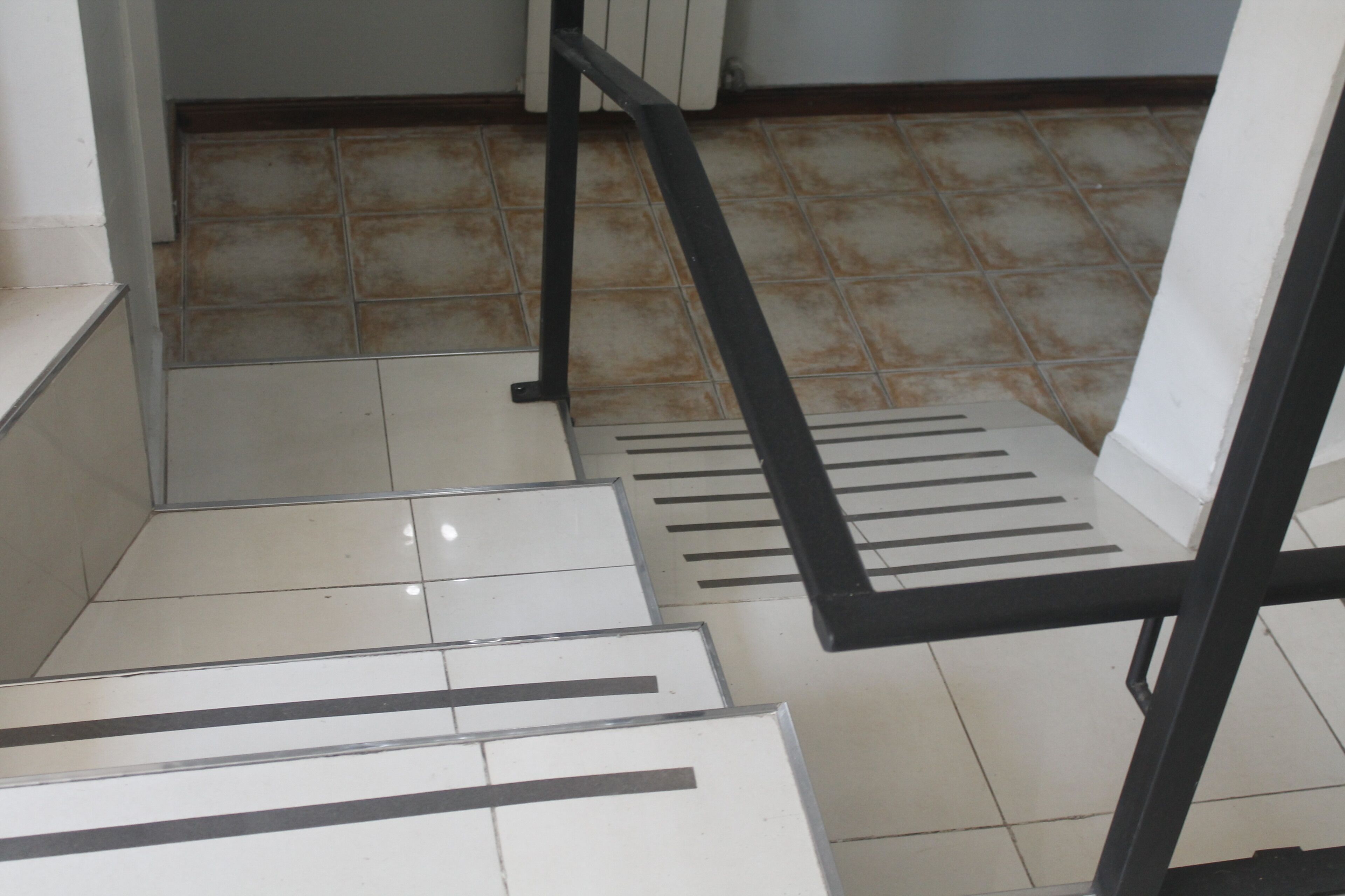 Una escalera con barandillas negras y baldosas blancas.