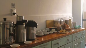 A breakfast bar with coffee makers, cups, and pastries. - Hotel Sienna (Mendoza)