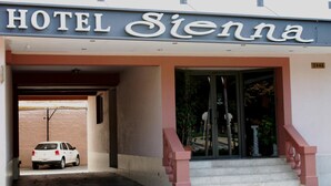 The entrance to HOTEL Sienna with a car parked in the driveway. - Hotel Sienna (Mendoza)