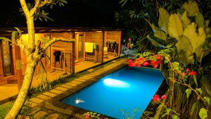 Une piscine entourée d’une terrasse en bois et d’une végétation luxuriante.