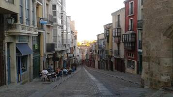 Una calle estrecha flanqueada por edificios, algunos con balcones y tiendas en la planta baja.