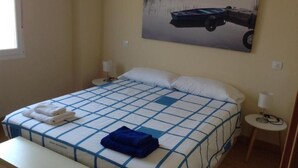 A bedroom with a bed, two bedside tables, a window, and a painting on the wall. - Zamora Apartments (Zamora)