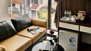 A modern living room with a leather sofa, a glass coffee table, and a laptop. A window with curtains reveals a cityscape view. - Anh Nguyet Hotel Da Nang (Da Nang)