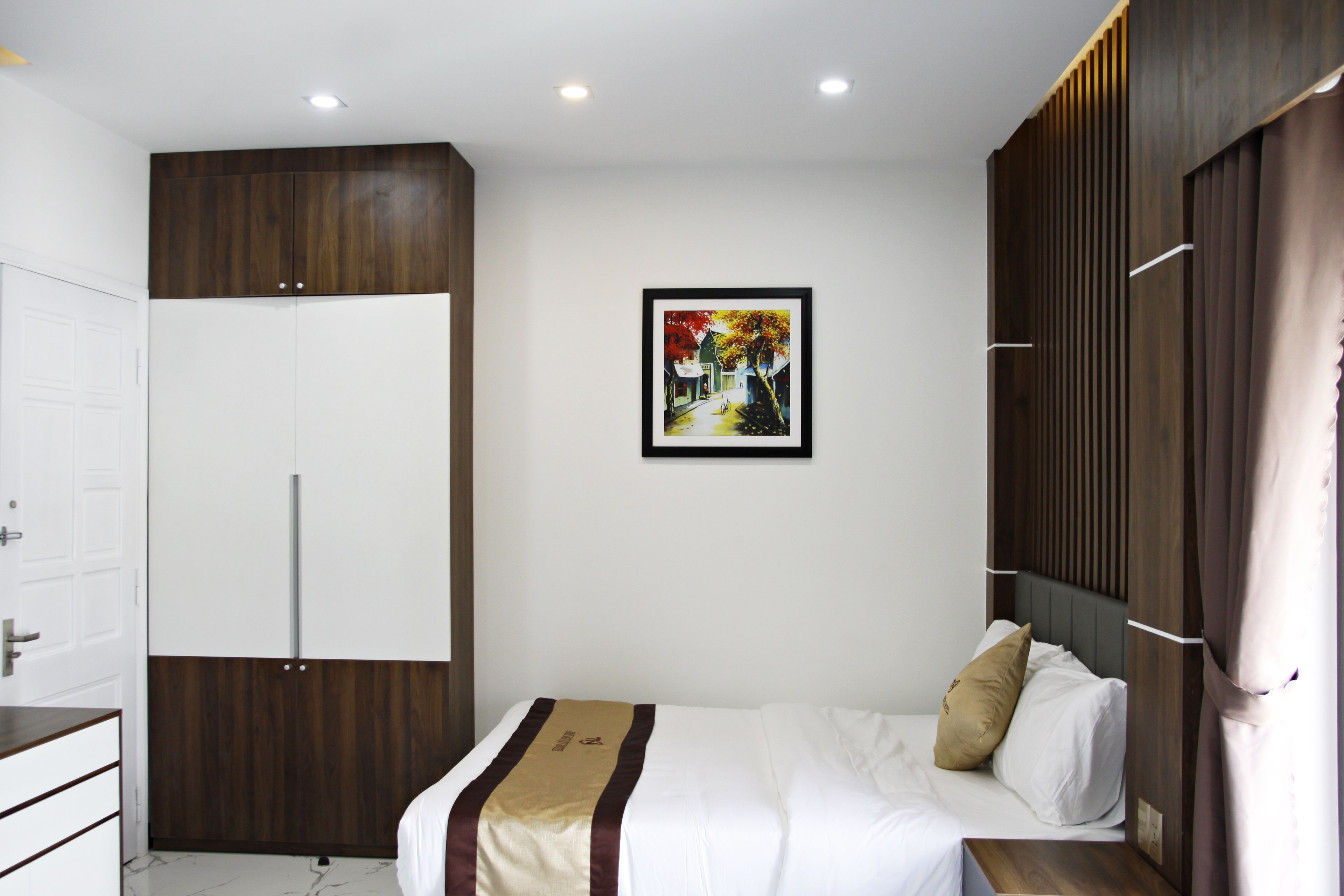 A bedroom with a bed, a wardrobe, a door, and a framed picture on the wall.