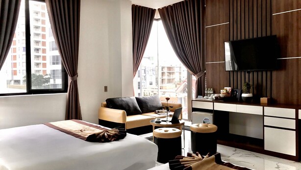 A hotel room with two beds, a desk, a TV, and a view of the city. - Anh Nguyet Hotel Da Nang (Da Nang)