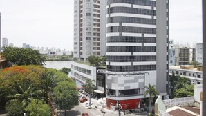 A modern high-rise building with a curved facade, surrounded by greenery and a body of water. - Anh Nguyet Hotel Da Nang (Da Nang)