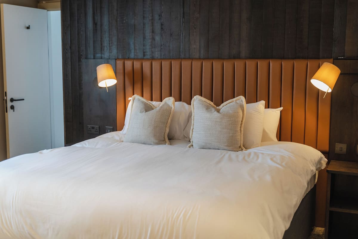 A hotel room with a large bed, two bedside lamps, and a wooden headboard.