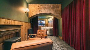 A theater lobby with a stone archway, plush seating, a fireplace, and a red curtain backdrop. - CODE - The Court, Edinburgh (Edinburgh)