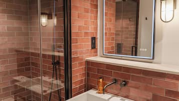 Une salle de bain avec une douche à parois de verre, un lavabo blanc et un miroir au-dessus du lavabo.