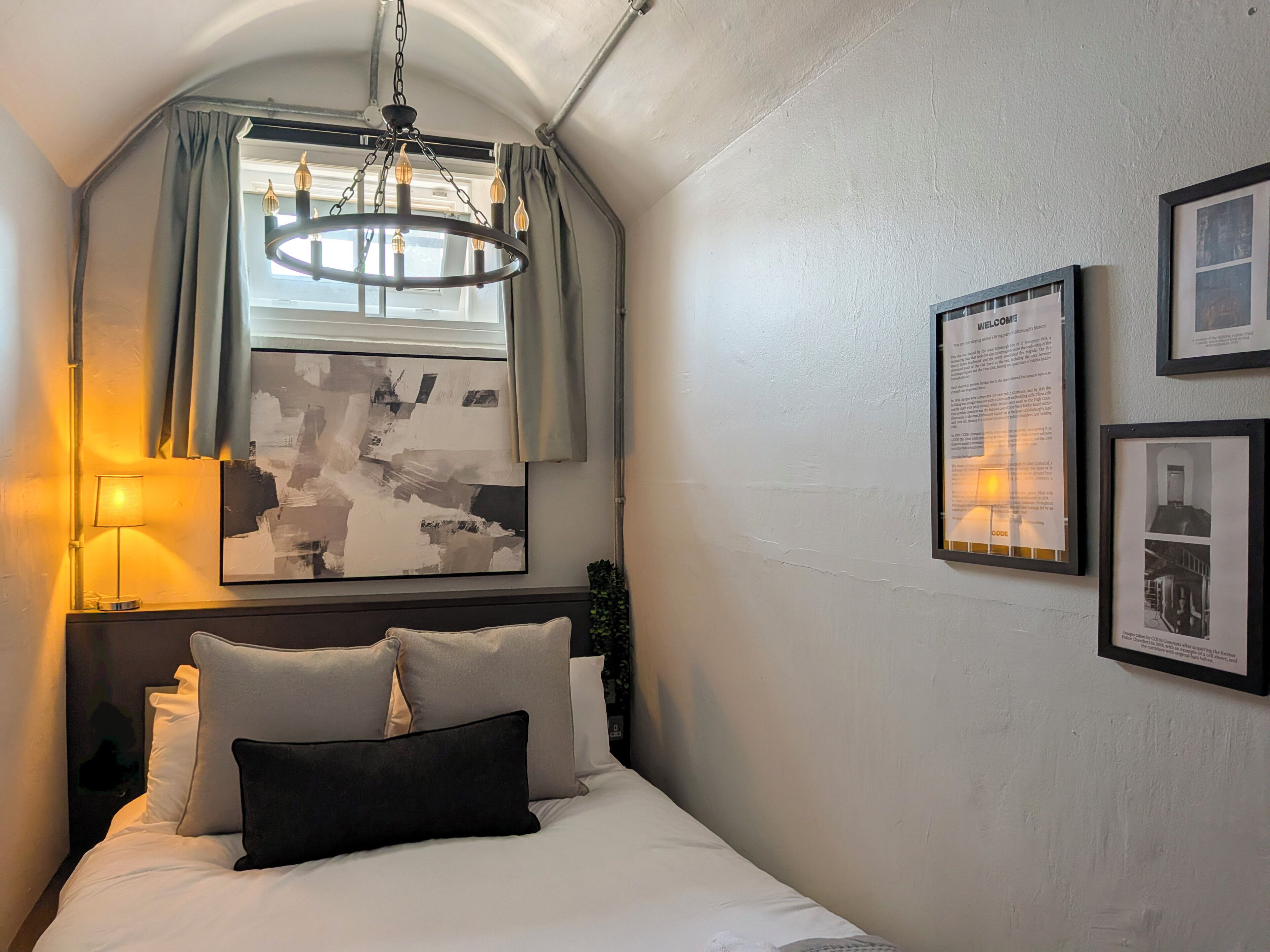 Un dormitorio con cama, candelabro, ventana con cortinas y decoración en la pared.