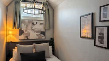 Un dormitorio con cama, candelabro, ventana con cortinas y decoración en la pared.