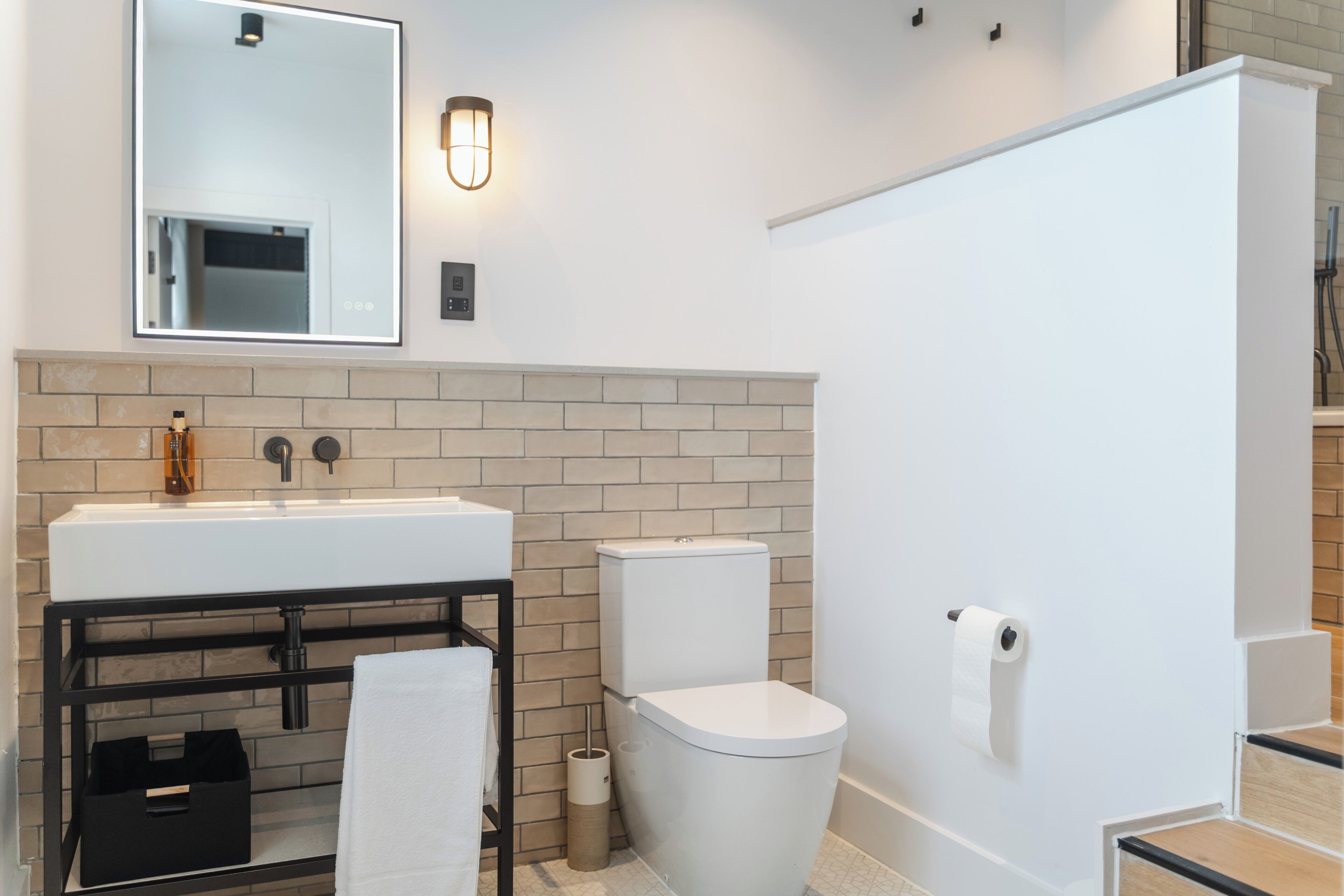 A modern bathroom with a white sink, a toilet, and a mirror above the sink.