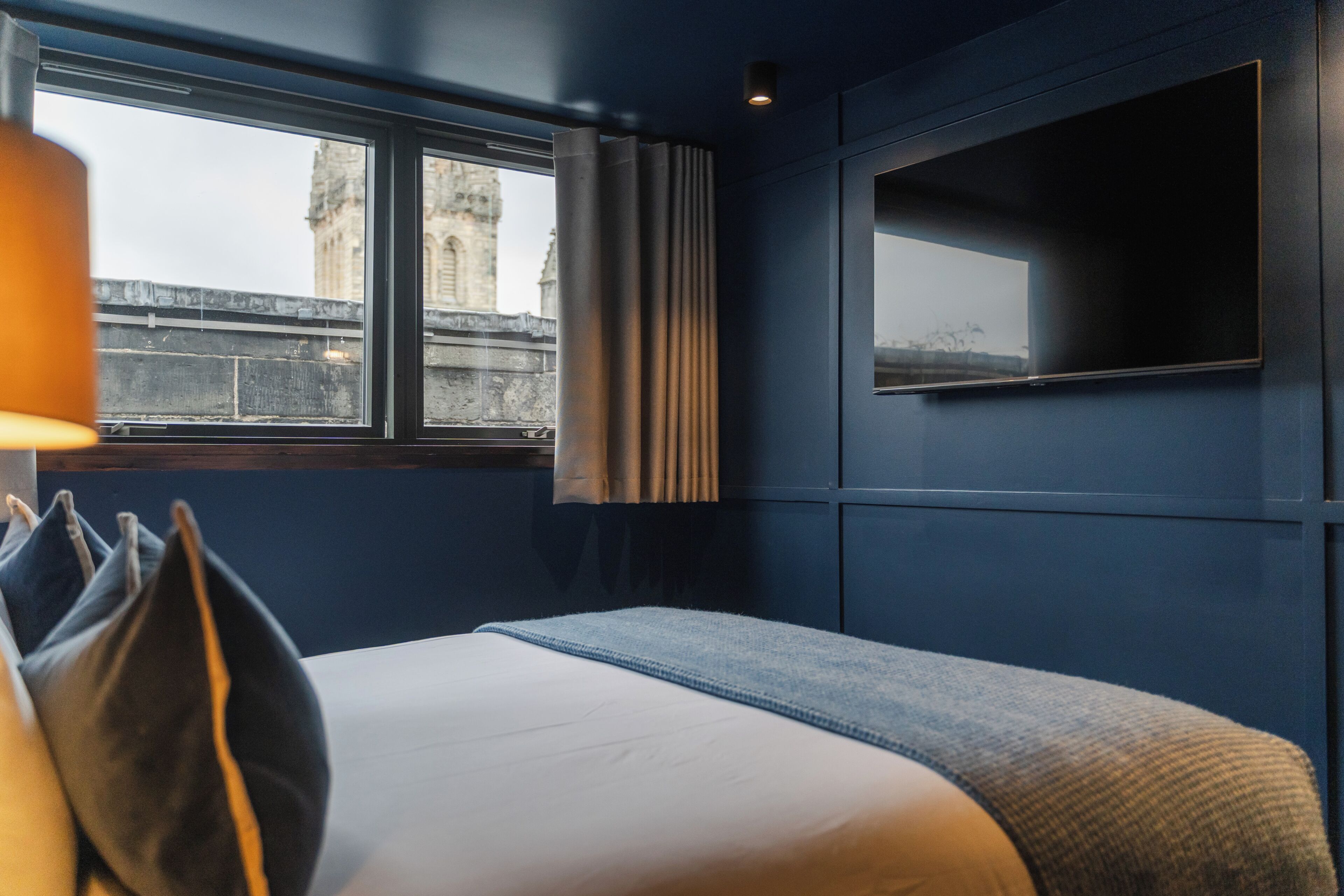 Una habitación de hotel con una cama grande, una ventana con cortinas y vista a un edificio.