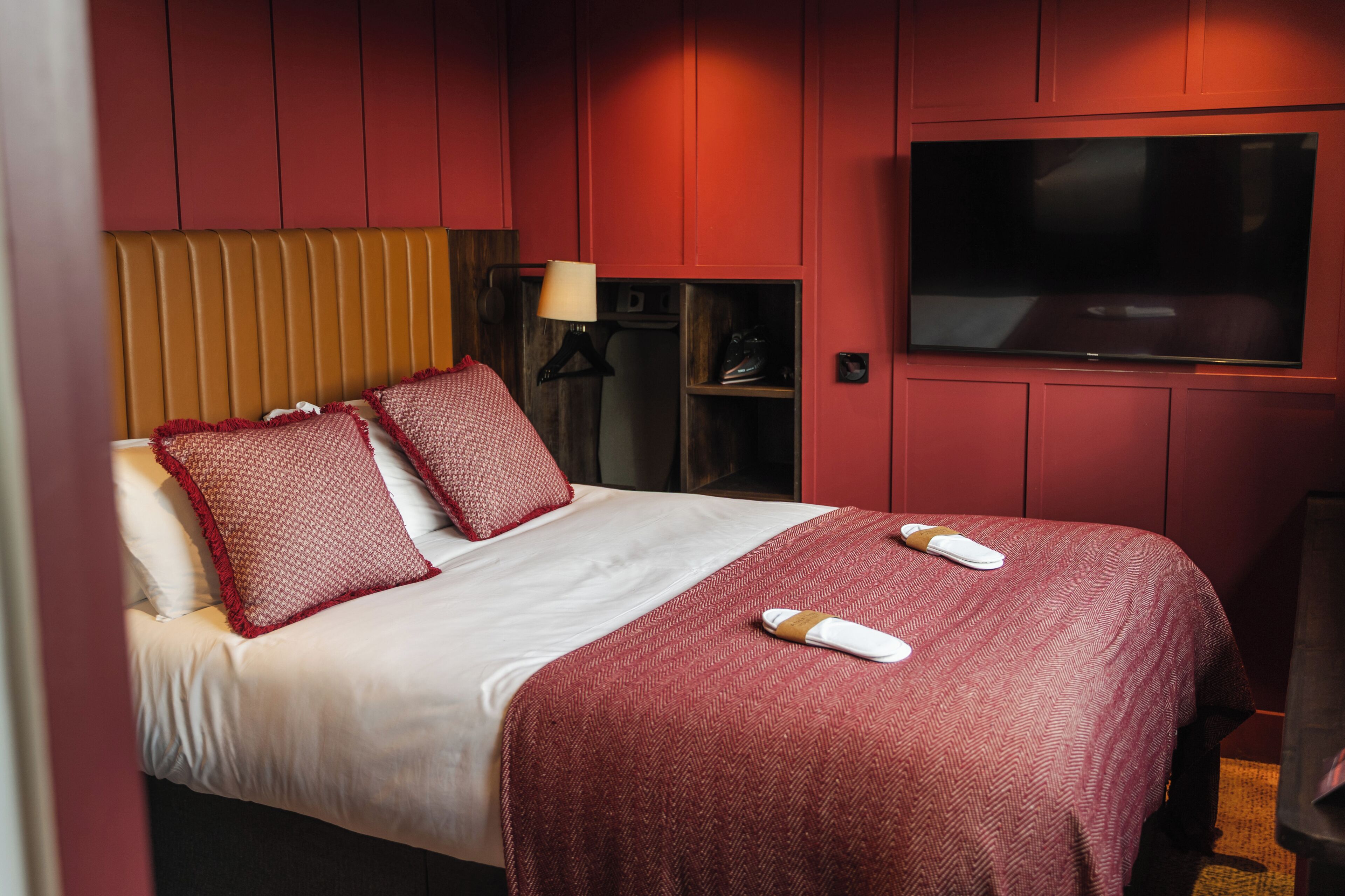 Habitación de hotel con cama, televisor y zapatero.