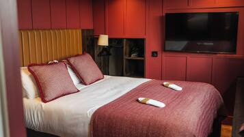 Habitación de hotel con cama, televisor y zapatero.