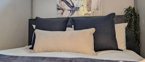 Un letto con una testiera, cuscini e una coperta.
