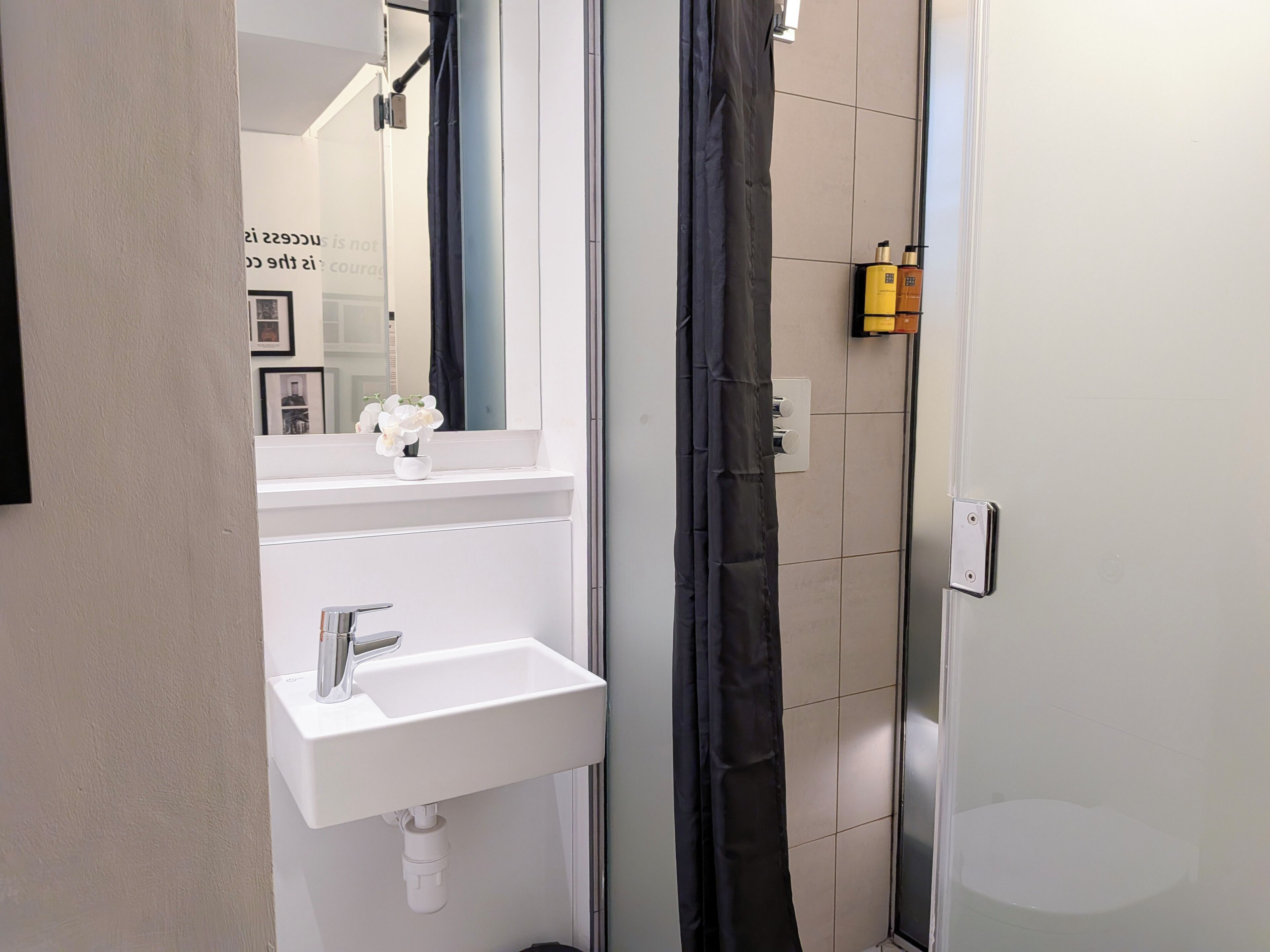 A bathroom with a white sink, a mirror, and a shower curtain.