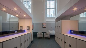 A hotel lobby with a long reception desk, lockers, and two armchairs. - CODE - The Court, Edinburgh (Edinburgh)