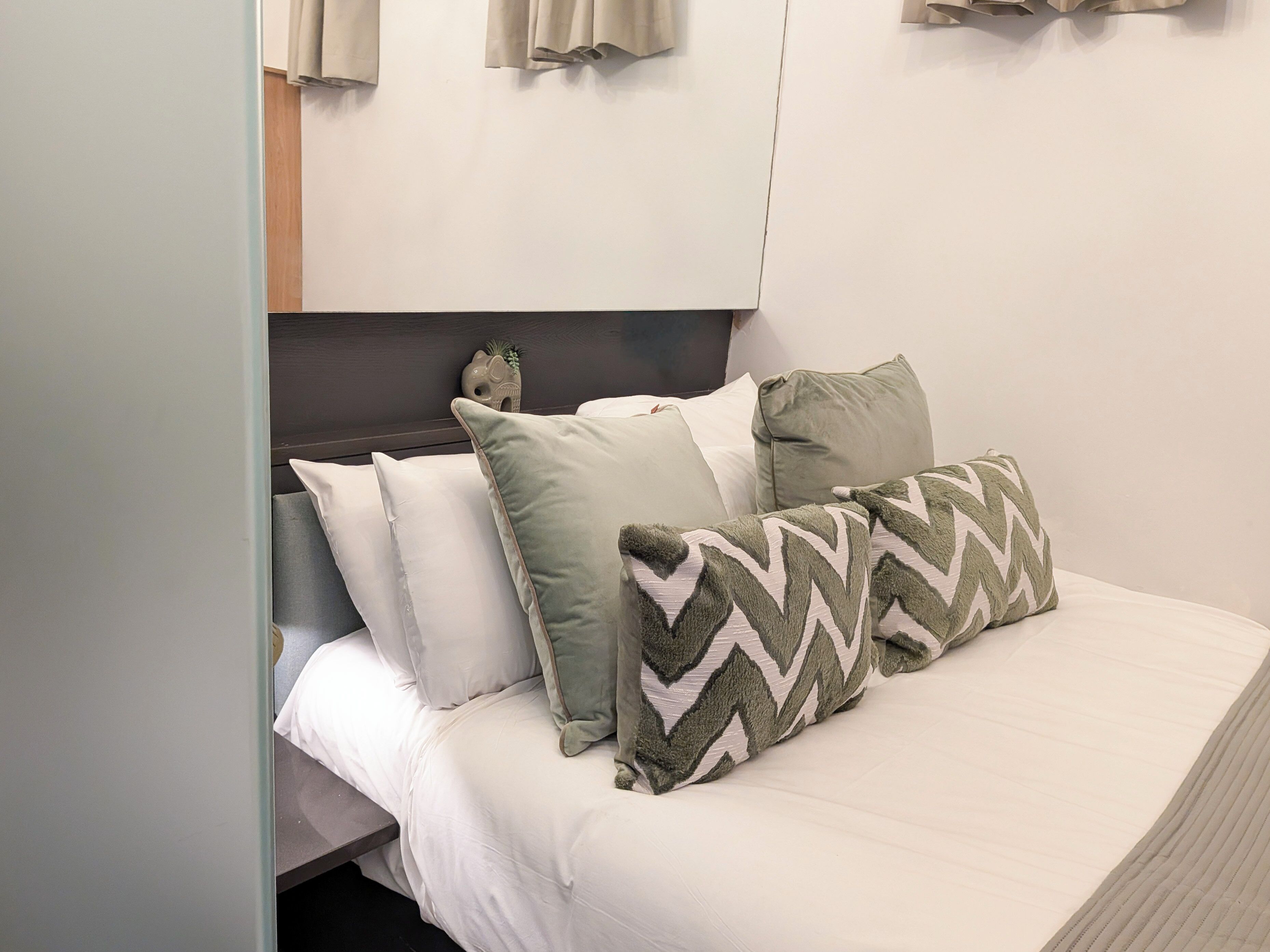 A bed with white bedding and multiple pillows, including a patterned one.
