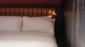 Una cama con ropa blanca y cabecera de listones verticales.