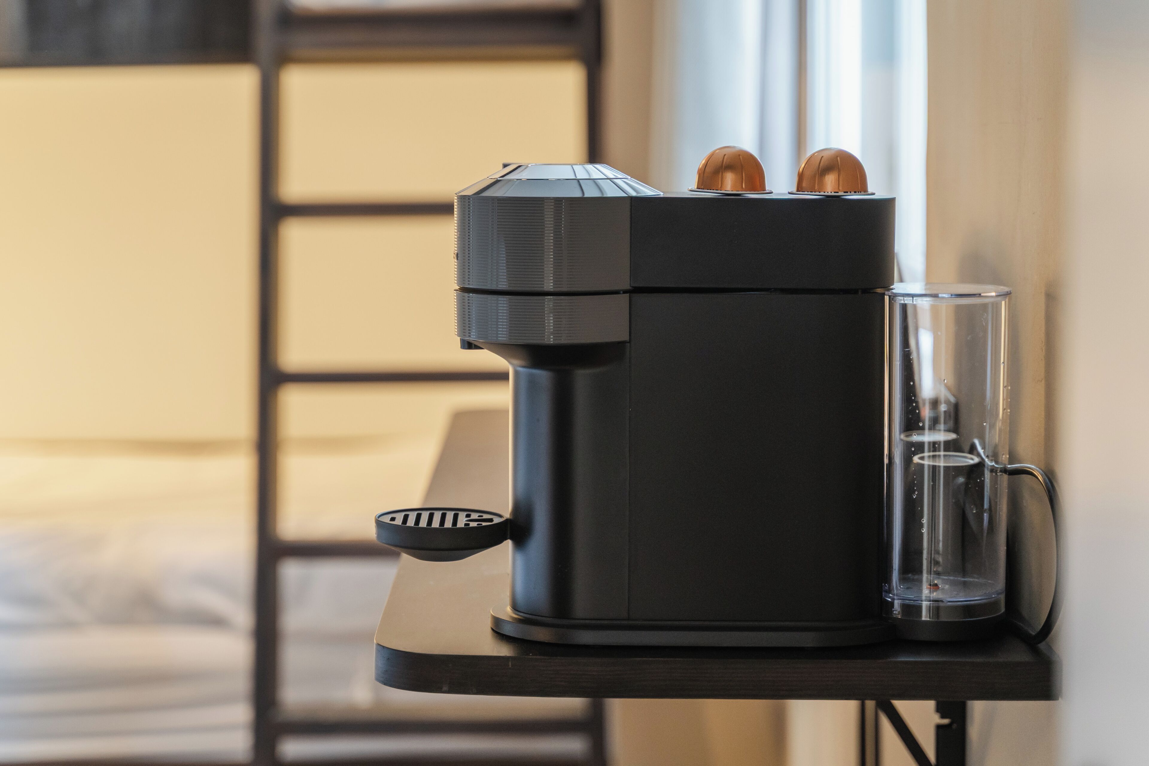 A coffee machine on a table with a glass of water beside it.
