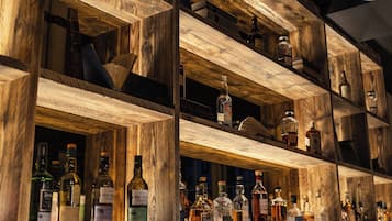 Une étagère en bois sur laquelle sont disposées différentes bouteilles d’alcool.