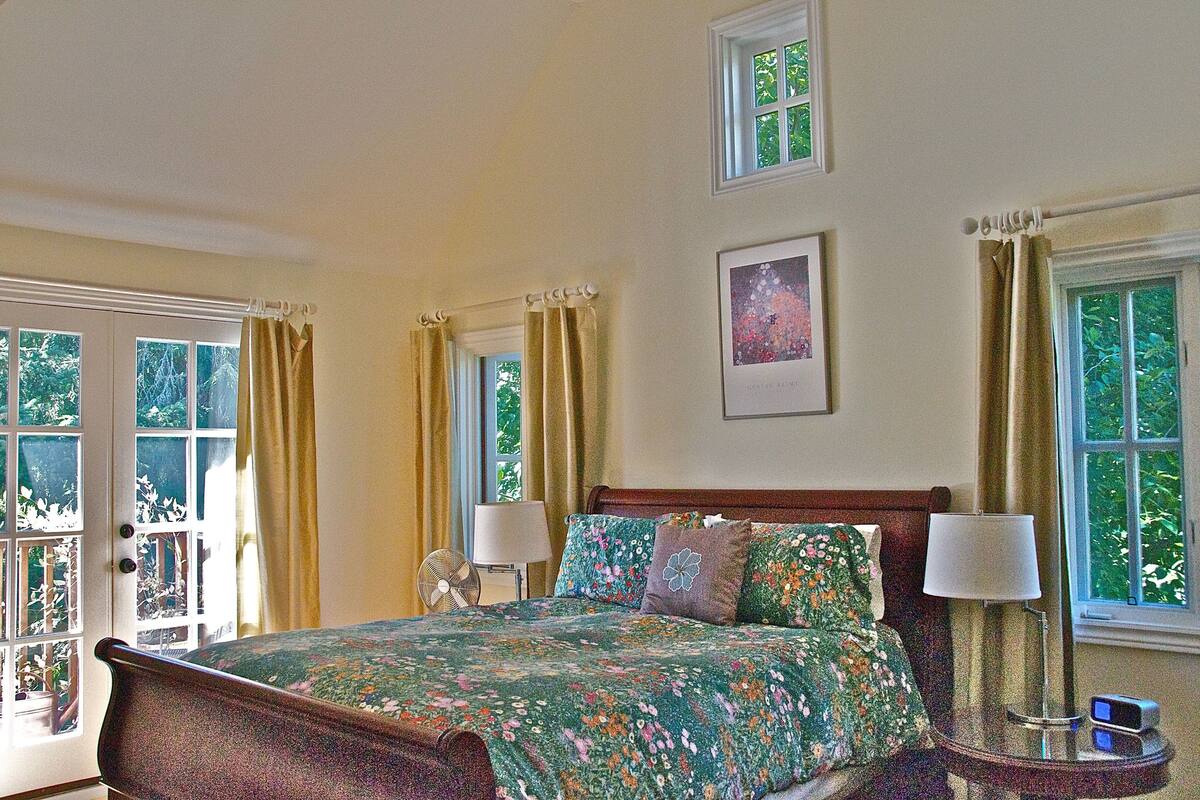 A bedroom with a bed, two bedside lamps, a nightstand, and a window with curtains.