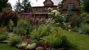 A large wooden house with a well-maintained garden in front. - Wetherly Inn (Salt Spring Island)