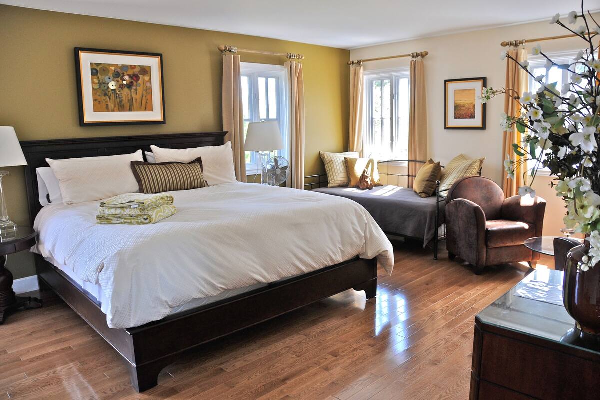 A well-furnished bedroom with a large bed, bedside tables, a chair, and a desk.