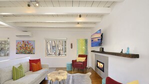A modern living room with a fireplace, a red armchair, a sofa with colorful cushions, and artwork on the walls. - Fully remodeled home in the heart of Historic Santa Fe - AC - Easy stroll to All (Santa Fe)