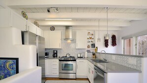 A modern kitchen with white cabinets, stainless steel appliances, and a large island with a sink. - Fully remodeled home in the heart of Historic Santa Fe - AC - Easy stroll to All (Santa Fe)