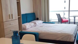 Ein Hotelzimmer mit Bett, Schreibtisch, Stuhl, Kleiderschrank und einem Fenster mit Vorhängen.