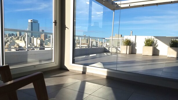 Eine moderne Wohnung mit großem Balkon, Blick auf die Stadt und einer Pergola mit Lichterketten.