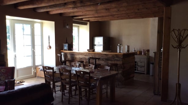 Una cocina rústica con una isla de piedra, sillas de madera y una mesa de comedor.