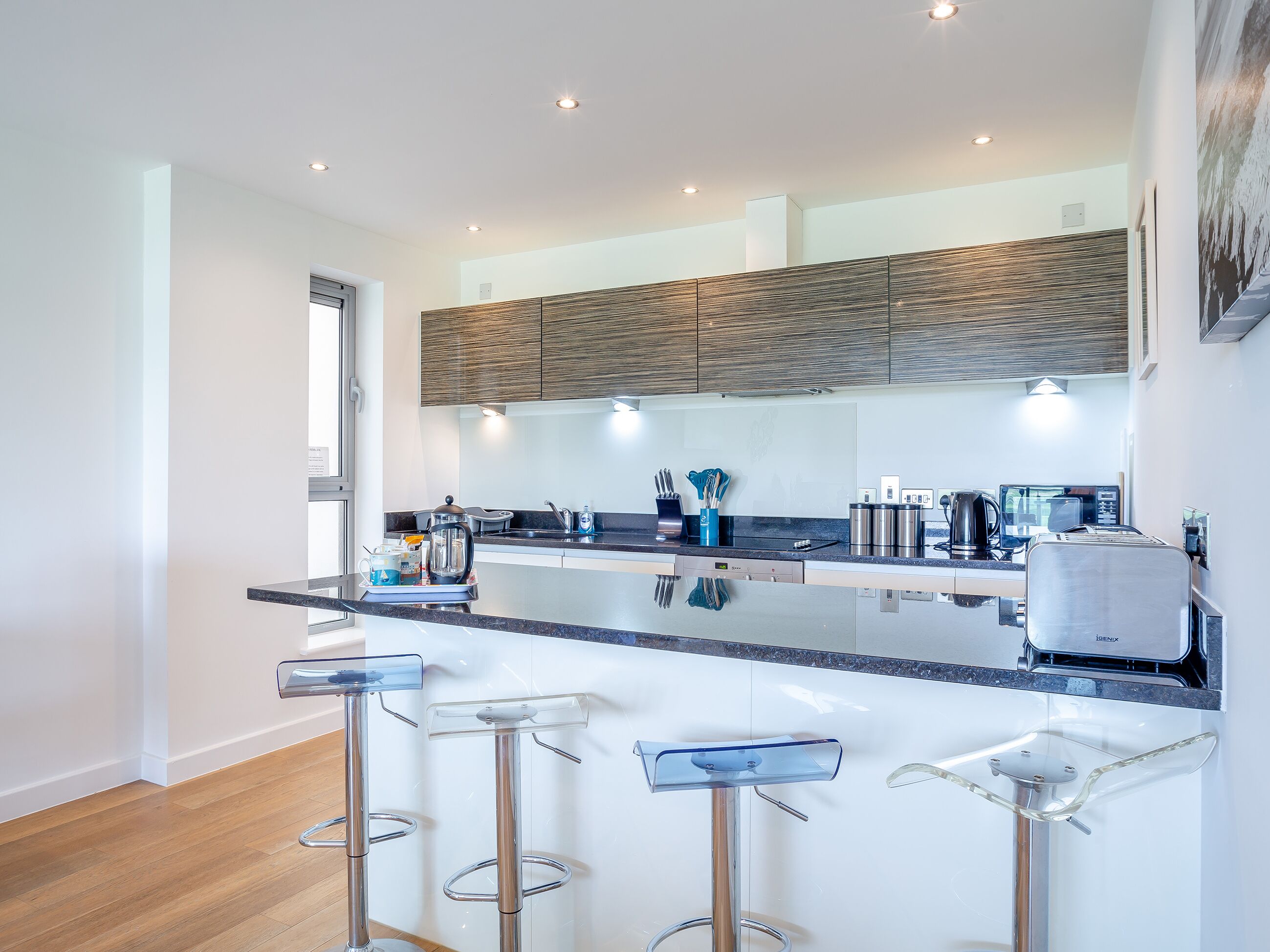 Una cucina moderna con isola centrale, elettrodomestici in acciaio inox e sgabelli da bar.