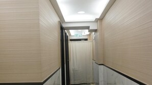 A hallway with marble flooring, beige walls, and a ceiling with recessed lighting. - Vve Vve Hotel (Kowloon)