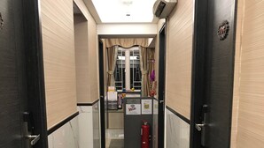 A hotel hallway with marble flooring, black doors, and a reception desk with a WiFi sign. - Vve Vve Hotel (Kowloon)