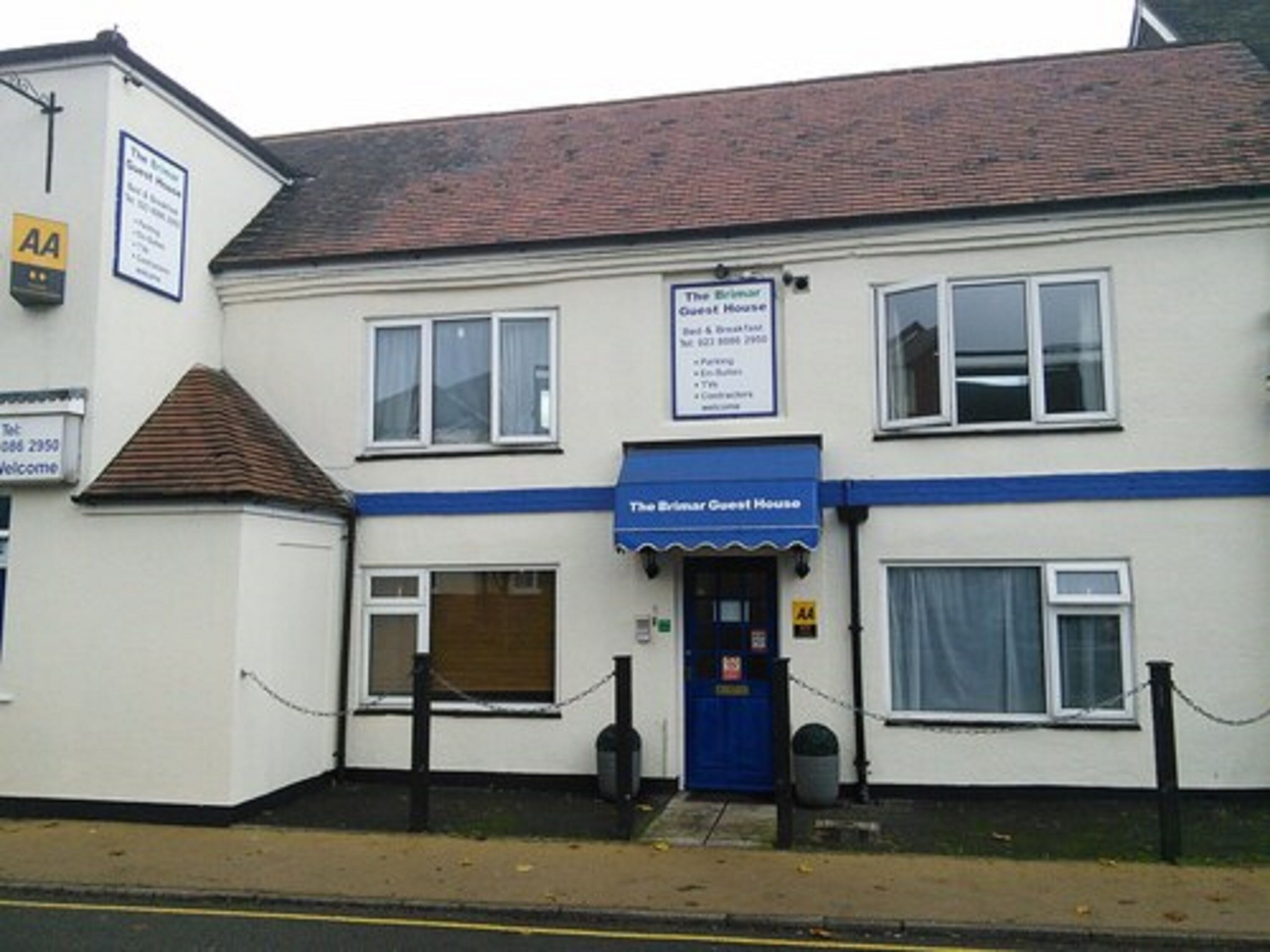 A two-story building with a blue awning labeled "The Brimar Guest House."