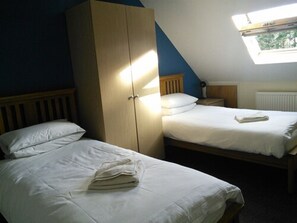 A bedroom with two single beds, a wardrobe, a window, and a radiator. - Brimar Guest House (Southampton)